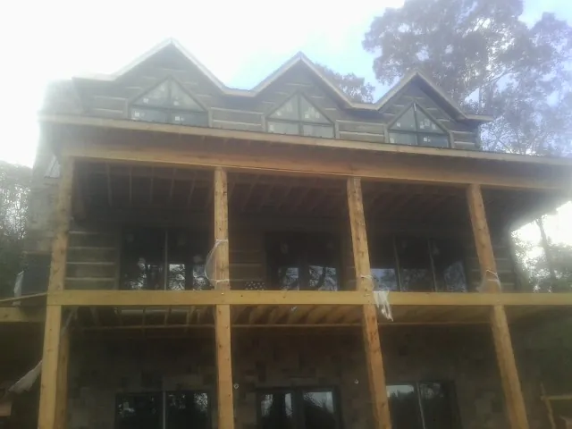 Dormers and porch framing on a large log home under construction — Roof Coating work by our crew in Luray